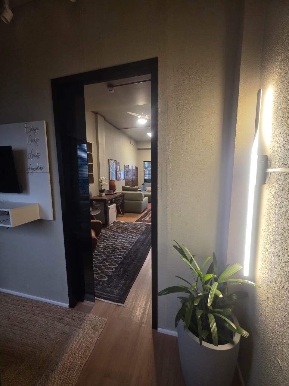 Sala 01 — lounge com sofá verde e parede de folhagem