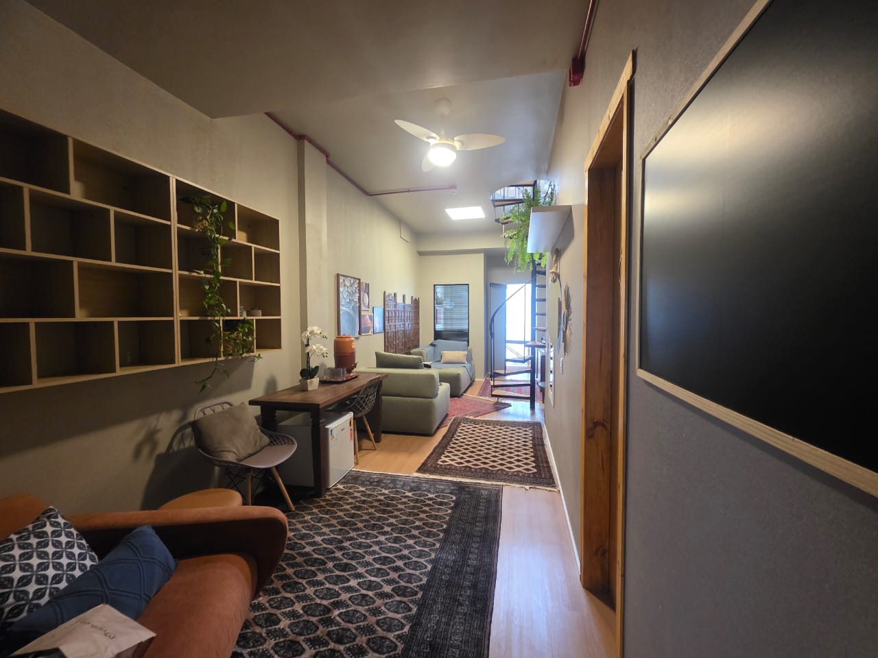 Sala 01 — ambiente principal com sofás e escada caracol