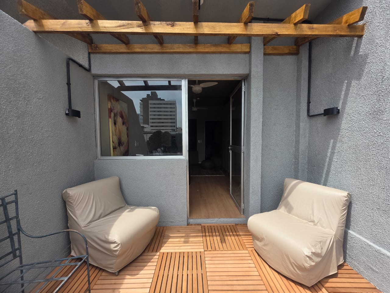 Sala 03 — terraço com pérgola de madeira e duas poltronas